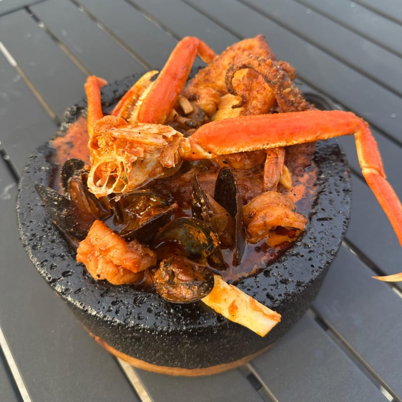 Seafood molcajete with crab legs, mussels, and octopus in a rich red sauce.